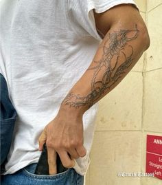 a man with a tattoo on his arm holding a cell phone in his left hand