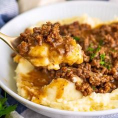 a spoonful of mashed potatoes topped with ground beef and gravy over mashed potatoes