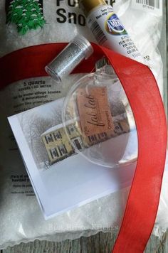 a christmas ornament is wrapped in red ribbon and next to some other items