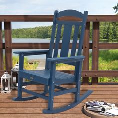 a blue rocking chair sitting on top of a wooden deck next to a lamp and lantern