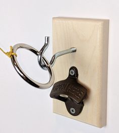 a pair of scissors is attached to a hook on a wooden block with two metal hooks