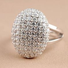 a silver ring with lots of white diamonds on it's sides, sitting on a beige surface