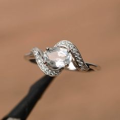 a close up view of a ring with an oval cut diamond on the top and side