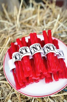 several red candles are on a plate in the hay