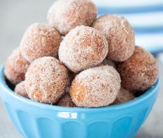 a blue bowl filled with sugar covered donuts