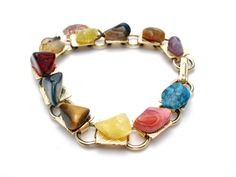 Multi Color Jewelry - This is a gold tone link bracelet with nugget gems of turquoise, amethyst, jasper, agate, tiger's eye, rhodocrosite and more. It has a round red enamel New Mexico charm that measures .5" in diameter, bracelet is 7" long and .38" wide. Multicolor Agate Gemstone Crystal Bracelet, Gold Bracelets With Agate And Natural Stones, Multi-stone Metal Bracelet, Multicolor Metal Bracelets With Stones, Vintage Multicolor Stone Bracelets, Multicolor Costume Jewelry Bracelets With Jewels, Vintage Multicolor Agate Jewelry, Multicolor Jewel Costume Jewelry Bracelets, Agate Stone Bracelet Jewelry