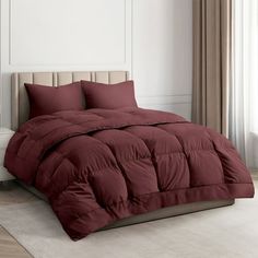 a bed with red comforter and pillows in a room next to a white wall