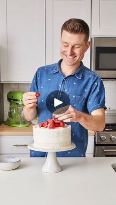 a man standing in front of a cake with strawberries on it and holding a knife