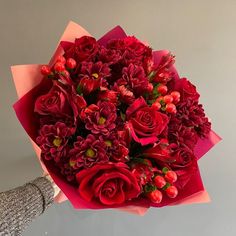 a woman holding a bouquet of red flowers