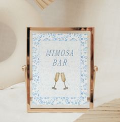 two champagne flutes in front of a minimosa bar sign on a white bed