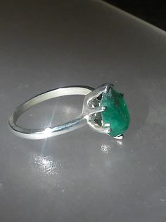 Imperfectly Perfect! This emerald came from a huge lot acquired in the late 70s. The natural inclusions in this stone along with the faceting on the back of the emerald make this ring so unique. This natural 1.56ct emerald is pear shaped cut and pavilion set (back of the stone is set face up). There is a natural clarity characteristic towards the lower tip of pear. Sterling silver mounting has five prongs and a v tip to protect the point of pear. High polished finish band tapers from 1.7 to 1.5 Faceted Emerald Ring Fine Jewelry, Fine Jewelry Faceted Emerald Ring, Hallmarked Green Emerald Gemstones, Faceted Emerald Anniversary Ring, Oval Emerald Gemstones With Prong Setting, Fine Jewelry Hallmarked Emerald Ring, Elegant Untreated Emerald Ring For Anniversary, Faceted Emerald Promise Ring, Tsavorite Emerald Ring