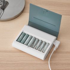 a white box with six tubes in it sitting on a table next to a lamp