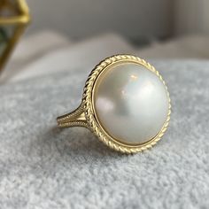 One piece of stunning statement piece made with large genuine mabe pearl and 14k solid gold * Center stone: Genuine White Mabe Pearl, 15-16mm in size * Ring measurement: 19.5mm wide, 1.2 to 1.6mm band thickness, 2.5mm bottom band width * Metal: 14K solid gold * Stamp: 14k ❤️Follow us on Instagram @ elekalonjewelry for latest projects and designs. *If you have any questions, please feel free to message us. Mabe Pearl Ring, Luxury Yellow Gold Pearl Ring With Cabochon, Elegant Round Cabochon Pearl Ring, Heirloom Pearl Ring With Cabochon, White Pearl Ring, June Birthstone Ring, Ring Pearl, Pearl Engagement Ring, Pearl Rings