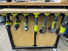 several electric drillers are lined up on a workbench in a workshop area