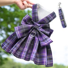 a hand holding a purple and black plaid bow with a keychain attached to it