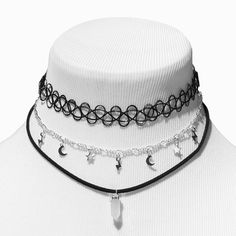 Complete your look with this choker set! It includes a stretch-fit black tattoo-style choker, a silver-tone figaro chain with celestial charms, and a black cord necklace with a white mystical gem. Layer them up for an on-trend look or wear them separately for a more subtle vibe.Pack Size: 3 Finish: Silver-tone Length: 12 + 3 in. extender / 30.48 + 7.62 cm. extender Closure: Lobster clasp, Stretch fit Material: Metal - Claire's White Mystical Gem, Celestial, & Black Tattoo Choker Necklaces - 3 Pa Choker Necklace Goth, Black Choker Aesthetic, Emo Choker, Chokers Black, Choker Aesthetic, Grunge Chokers, Black And White Jewelry, Black And White Necklace, Tattoo Choker Necklace