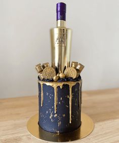 a cake decorated with gold and blue icing has a bottle of wine on top