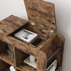 an open wooden box with magazines and books on it's shelf next to a phone