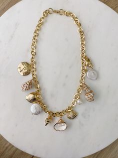 Look at this stuff isn’t it neat? A collection of pearls, seashells and charms, hanging from chunky gold chain, gives the option to continue your collection of shells or wear as is. Inspired by the beauty of captiva and it’s sea filled beaches, this necklace is all that’s glamorous about nature and summer. 18” long Gold filled charms and gold filled chains. Made in Miami Seashell Gold Jewelry, All About Jewelry, Real Shell Jewelry, Summer Gold Necklace, Seashell Charm Bracelet, Chunky Gold Charm Necklace, Trendy Beach Jewelry, Summer Charm Necklace, Sea Shell Jewelry Aesthetic