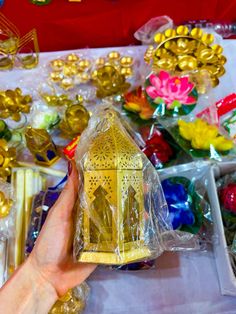 a hand is holding a small gold lantern in front of many other ornaments and decorations