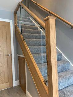 a stair case with glass railing and wooden handrail