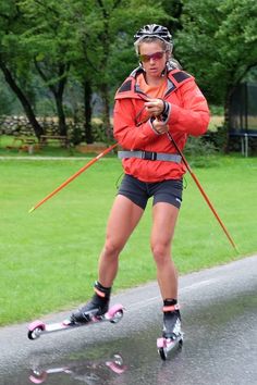 a woman in an orange jacket is rollerblading down the road with her poles