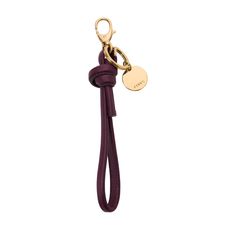 a keychain with a leather cord and a gold plated charm on it