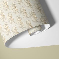 a lamp shade with gold sunburst pattern on the wall next to a white table