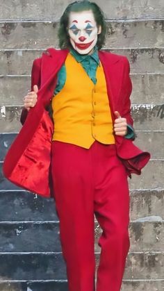 a man dressed as the joker standing in front of stairs