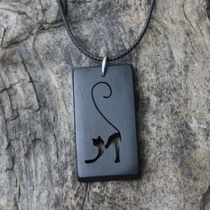 a wooden pendant with a black cat on it