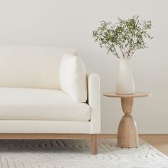 a white couch sitting next to a wooden table on top of a carpeted floor