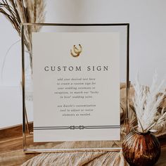 a wedding sign sitting on top of a table next to a vase with dried flowers