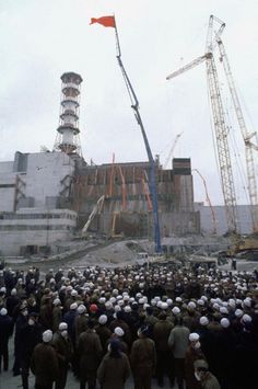 a large group of people standing around in front of a building with cranes on it