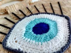 an eyeball made out of crocheted yarn on top of a woven piece of cloth