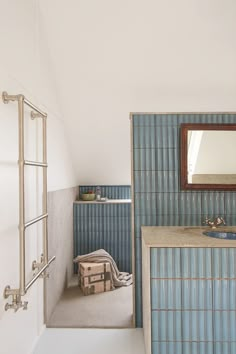 a bathroom with blue tiles on the walls and floor, along with a mirror above the sink