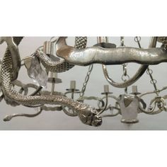 a metal chandelier with snakes and leaves hanging from it's center piece