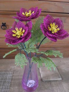 three purple flowers in a vase on a table