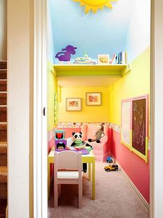 the hallway is painted bright yellow, pink and blue with toys on the table in the corner