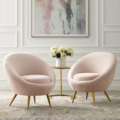 two pink chairs sitting next to each other in front of a painting