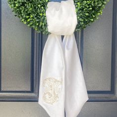 a pair of white towels hanging on the front door with a boxwood wreath behind it