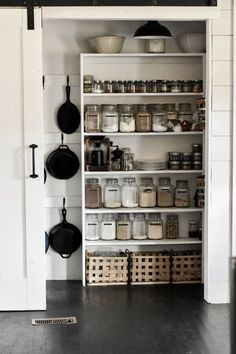 an open pantry with pots and pans on the shelves