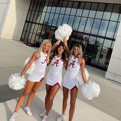 three cheerleaders are posing in front of a building