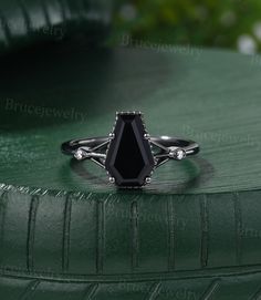 a black stone ring sitting on top of a green surface