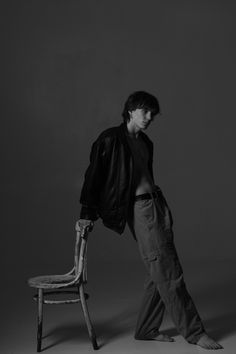 a man standing next to a wooden chair