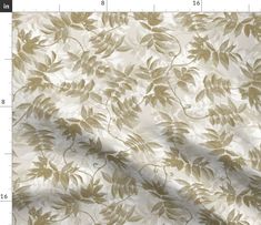 a close up view of the fabric with leaves on it in gold and white colors