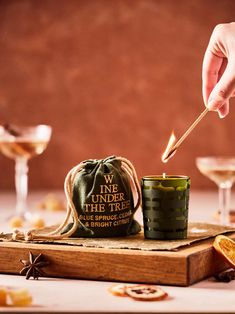 a person lighting a candle in front of a bag with the words wine under the tree on it