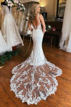 a woman in a wedding dress looking back at the bride's gown on display