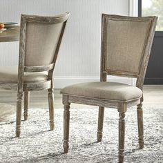 a dining room table with two chairs and a rug on the floor in front of it