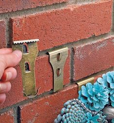 a hand is holding an open door handle on a brick wall with blue pine cones