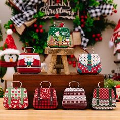 several christmas themed purses are on display in front of a wreath and other holiday decorations